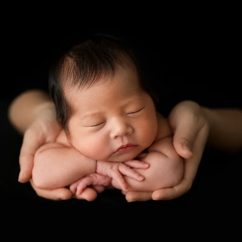 Bebé recién nacido sostenido con cuidado entre las manos de sus padres